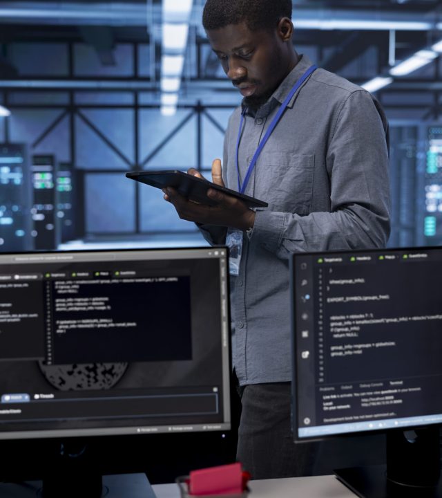 Admin in data center using diagnostic tools and system monitoring software on tablet device to identify root cause of errors. IT professional in server farm repairing infrastructure